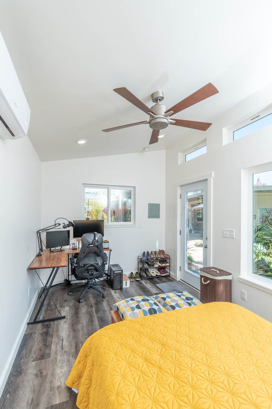 A modern home with dark floors with a desk and bed, provided by one of the best Orlando affordable tiny home builders.