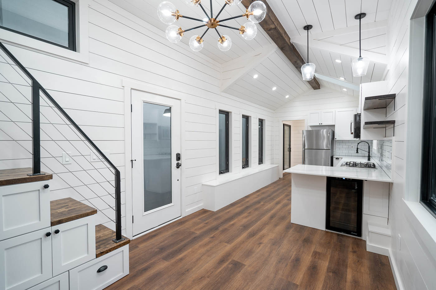 A modern home with dark floors and white kitchen cabinets, provided by one of the best tiny house companies.